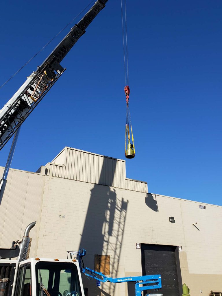 Our rigging contractors in Michigan lift a piece of equipment outside with a crane